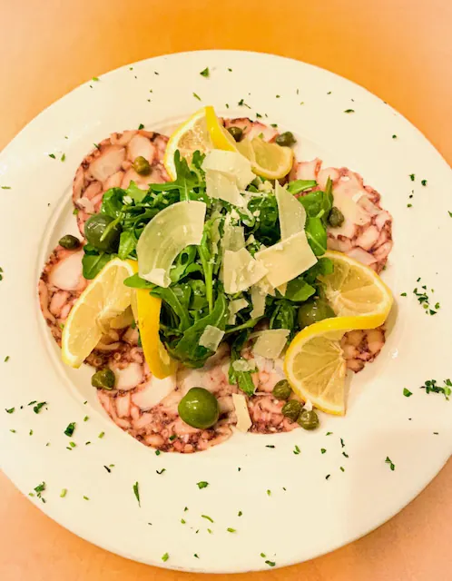 Carpaccio with arugula, shaved cheese and lemon