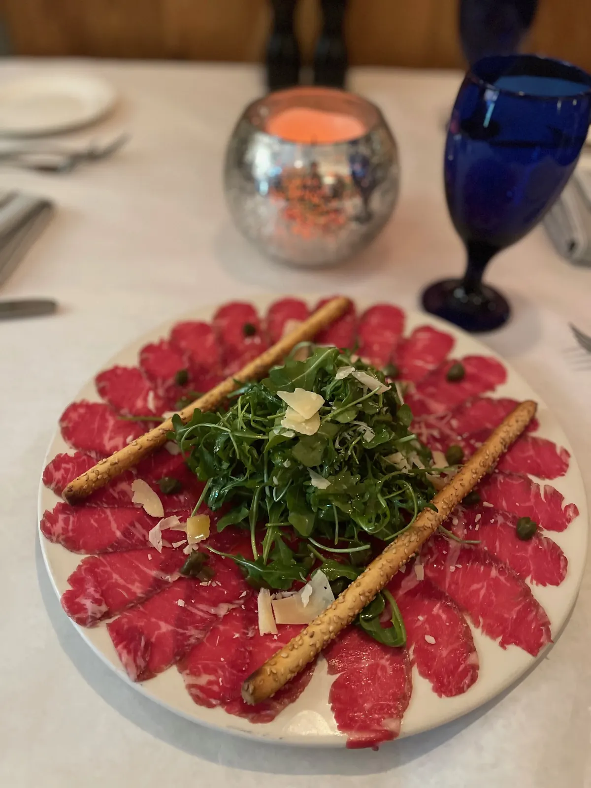 A carpaccio plate topped with arugula