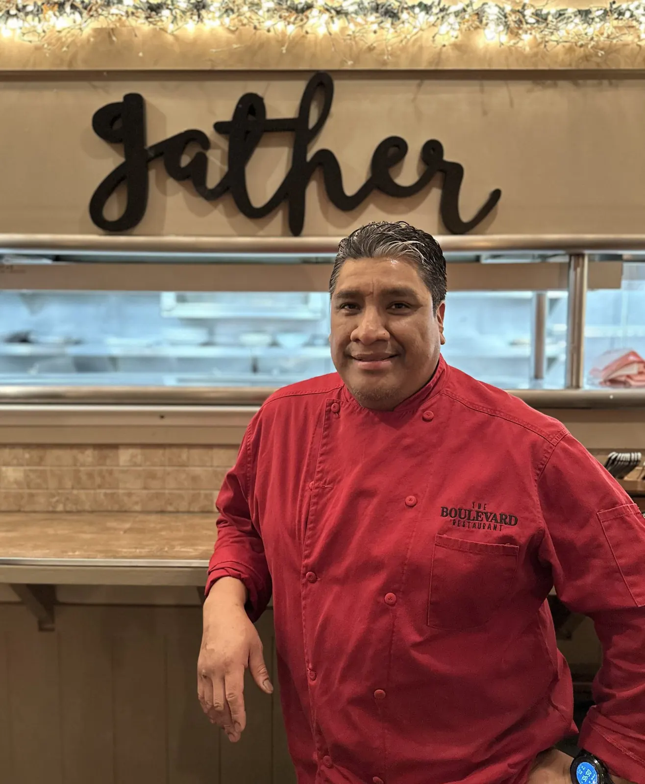 Chef in a red chef’s coat in front of a Gather sign