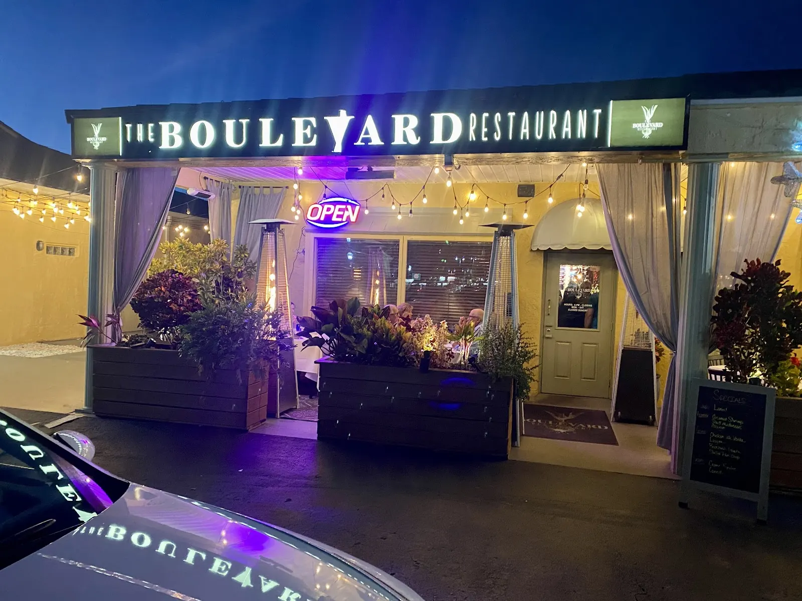 The Boulevard Restaurant storefront lit up at night in Heritage Square